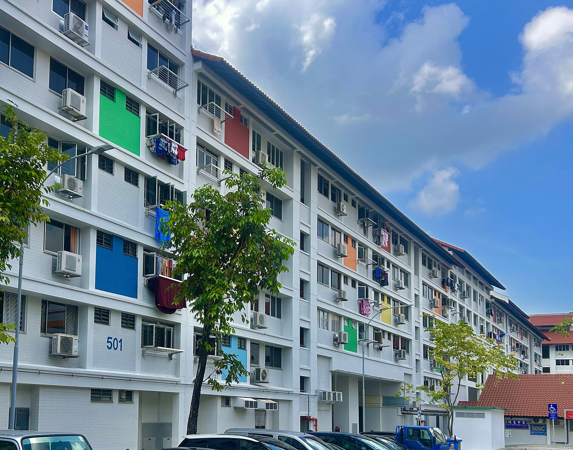 HDB apartment block 501 in Bishan, seen from below against a pale sky, with repeating balconies and shuttered windows.
